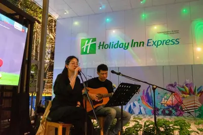 a woman and a man playing a guitar and a microphone at Holiday Inn Express Bangkok Soi Soonvijai by IHG in Bangkok