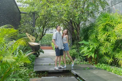 a man and woman standing on a bridge in a garden at Holiday Inn Express Bangkok Soi Soonvijai by IHG in Bangkok