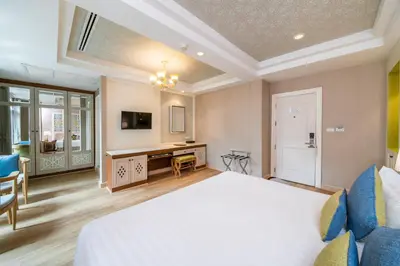 a bedroom with a large bed and a desk at La Petite Salil Sukhumvit 8 in Bangkok