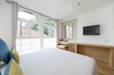 a bedroom with a bed and a tv on a wall at La Petite Salil Sukhumvit 8 in Bangkok