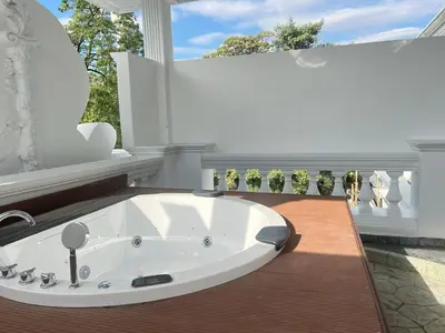 a bathroom with a large white tub on a balcony at V20 Boutique Jacuzzi Hotel in Bangkok
