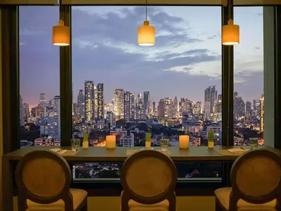 a restaurant with a view of a city from a window at Grand Mercure Bangkok Atrium in Bangkok