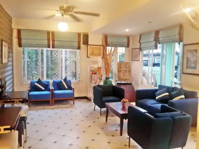a living room with blue couches and tables and windows at Sawasdee Sukhumvit Inn in Bangkok