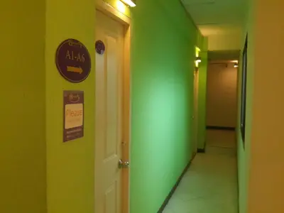 a hallway with green walls and a sign on a door at Sawasdee Sukhumvit Inn in Bangkok