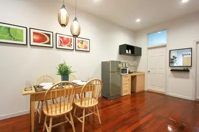 a kitchen and dining room with a table and a refrigerator at The Serene House Bangkok in Bangkok