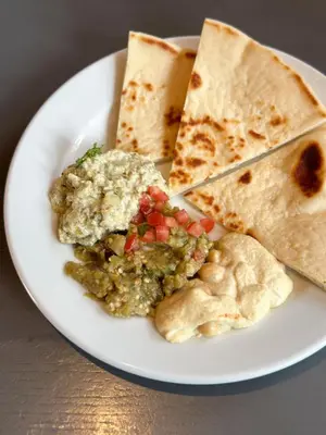 a plate of food with guacamole and pita bread at Urbana Langsuan Hotel in Bangkok