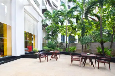 a courtyard with tables and chairs and palm trees at Urbana Langsuan Hotel in Bangkok