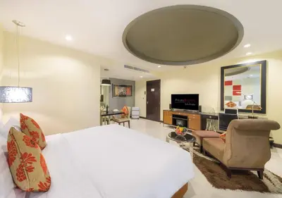 a bedroom with a large bed and a living room at FuramaXclusive Asoke, Bangkok in Bangkok