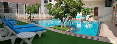 a pool with blue chairs and trees in a building at FuramaXclusive Sathorn, Bangkok in Bangkok