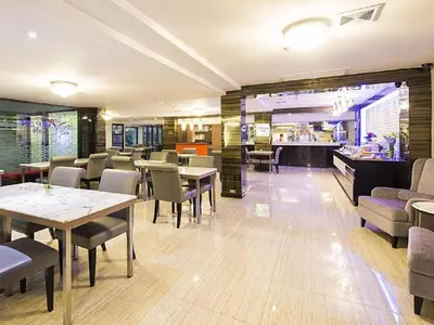 a restaurant with tables and chairs and a kitchen at Aspen Suites Hotel Sukhumvit 2 in Bangkok