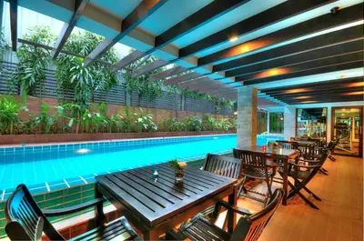 a pool with tables and chairs next to a swimming pool at Aspen Suites Hotel Sukhumvit 2 in Bangkok