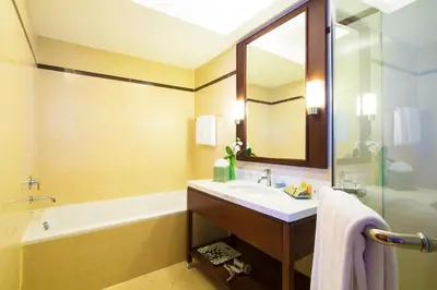 a bathroom with a sink and a tub and a mirror at Column Bangkok Hotel in Bangkok