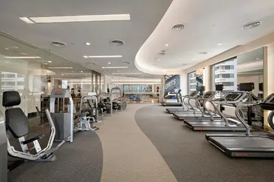 a gym with a row of treadmills and machines at Grande Centre Point Hotel Ratchadamri Bangkok in Bangkok
