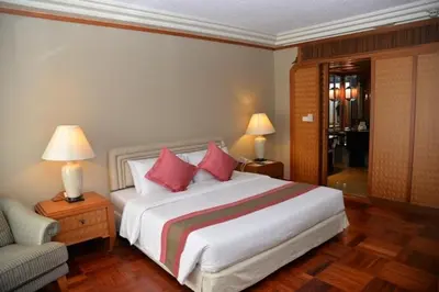 a bedroom with a large white bed with red pillows at Rama Gardens Hotel Bangkok in Bangkok