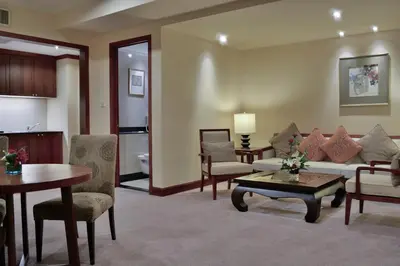 a living room with a couch and a table and chairs at Rama Gardens Hotel Bangkok in Bangkok