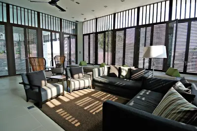 a living room with a couch and chairs and windows at Somerset Park Suanplu Bangkok in Bangkok