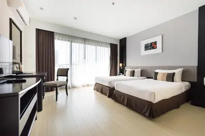 a hotel room with two beds and a television at Somerset Park Suanplu Bangkok in Bangkok