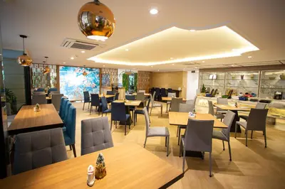 a restaurant with wooden tables and chairs and a cafeteria at Club Mahindra Mac Boutique Hotel in Bangkok