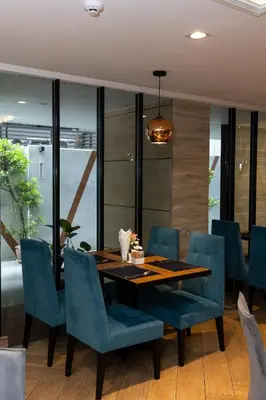 a dining room with a wooden table and blue chairs at Club Mahindra Mac Boutique Hotel in Bangkok
