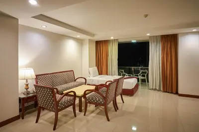 a hotel room with a bed and a table and chairs at Nana Hiso Hotel in Bangkok