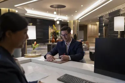 a man sitting at a desk writing on a piece of paper at Crowne Plaza Bangkok Lumpini Park by IHG in Bangkok