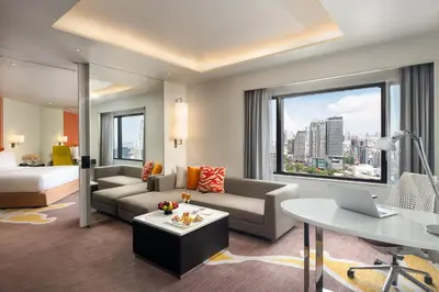 a living room with a couch and a table with a laptop at Crowne Plaza Bangkok Lumpini Park by IHG in Bangkok