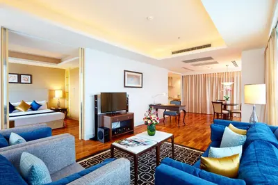 a living room with blue furniture in a hotel room at The Duchess Hotel in Bangkok