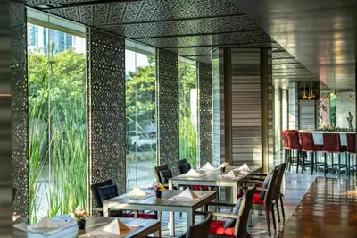 a restaurant with tables and chairs and large windows at TUI BLUE Maduzi Hotel Bangkok in Bangkok