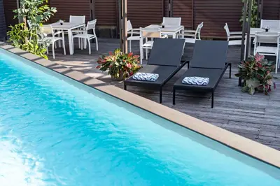 a swimming pool with two chairs and tables and a table and chairsitures at TUI BLUE Maduzi Hotel Bangkok in Bangkok
