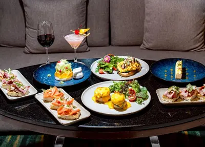 a table with plates of food and a glass of wine at Rembrandt Hotel Bangkok in Bangkok