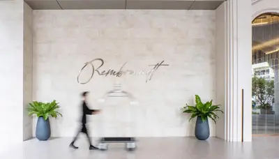 a man walks past a sign for a store at Rembrandt Hotel Bangkok in Bangkok