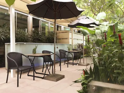a patio with tables and chairs and an umbrella at Refillnow! Hostel in Bangkok