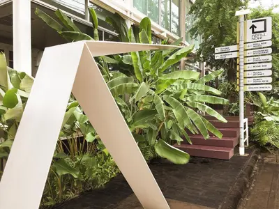a street sign in front of a building with plants at Refillnow! Hostel in Bangkok