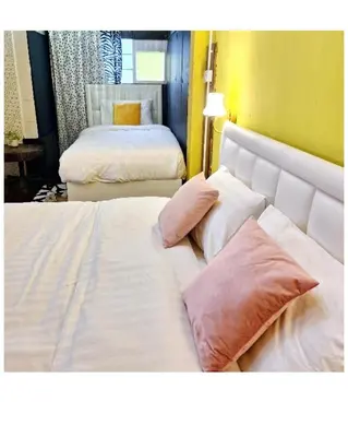 two beds in a hotel room with white sheets and pillows at DDM House in Bangkok