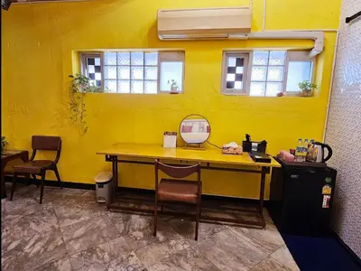 a yellow wall with a table and chairs in a room at DDM House in Bangkok