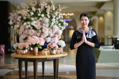 a woman standing in front of a table with areath of flowers at Miracle Grand Convention Hotel in Bangkok