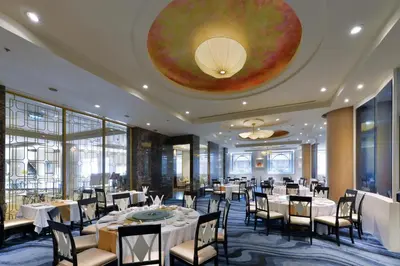 a dining room with tables and chairs and a large ceiling at Miracle Grand Convention Hotel in Bangkok