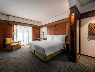 a hotel room with a bed and a chair at The Sukhothai Bangkok in Bangkok
