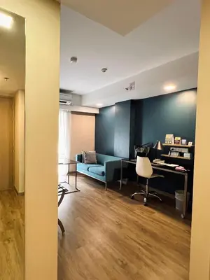 a living room with a blue couch and a desk at Citadines Sukhumvit 8 Bangkok in Bangkok