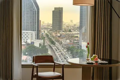 a room with a table and a window with a view of a city at Montien Hotel Surawong Bangkok in Bangkok