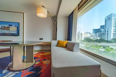 a living room with a table and a couch and a window at Montien Hotel Surawong Bangkok in Bangkok