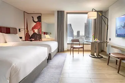 a hotel room with a bed and a desk and a window at Montien Hotel Surawong Bangkok in Bangkok
