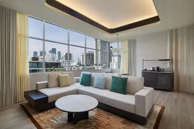 a living room with a couch and a large window at DoubleTree by Hilton Bangkok Ploenchit in Bangkok