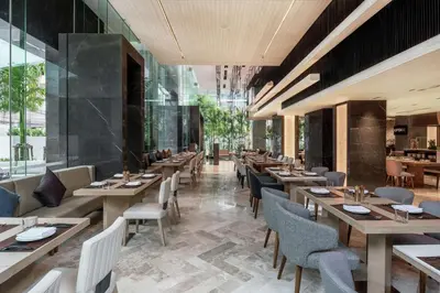 a restaurant with wooden tables and chairs and windows at DoubleTree by Hilton Bangkok Ploenchit in Bangkok