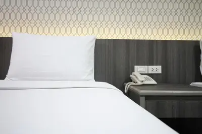 a bedroom with a bed and a phone next to a desk at Convenient Park Bangkok in Bangkok