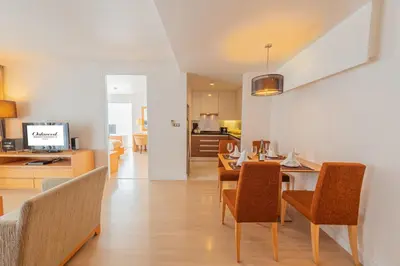 a dining room and living room with a table and chairs at Oakwood Residence Sukhumvit 24 Bangkok in Bangkok