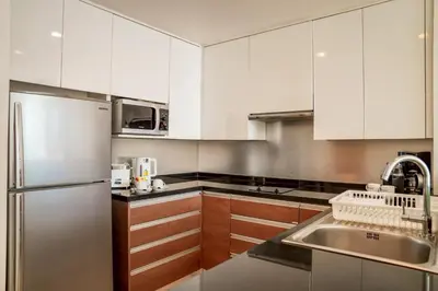 a kitchen with white cabinets and a stainless steel refrigerator at Oakwood Residence Sukhumvit 24 Bangkok in Bangkok