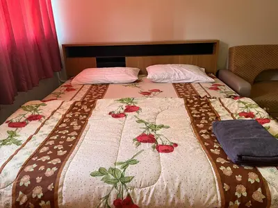 a bed with a bedspread with flowers on it at Popular Condo by Jintana in Pak Kret
