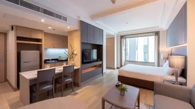 a hotel room with a bed and a dining room at Jasmine City Hotel in Bangkok