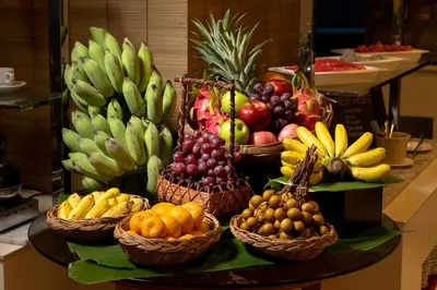 a display of fruits and vegetables in baskets on a counter at Jasmine City Hotel in Bangkok